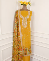 Yellow embroidered dress with a patterned dupatta on a mannequin against a white wall.